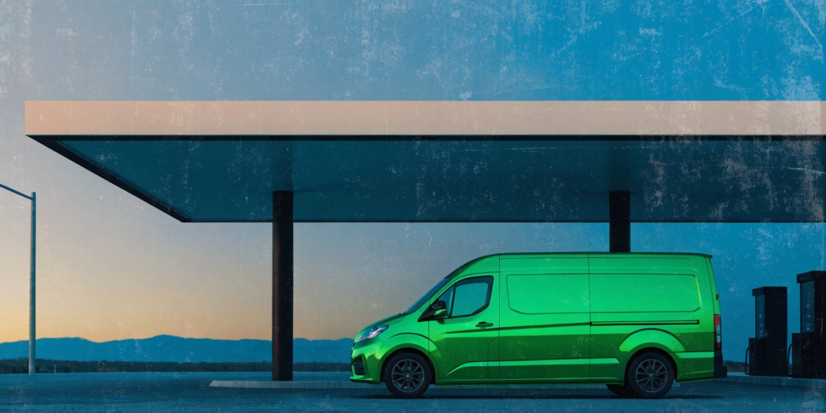 A modern unbadged diesel panel van at a quiet fuel forecourt beneath a wide canopy in low evening light