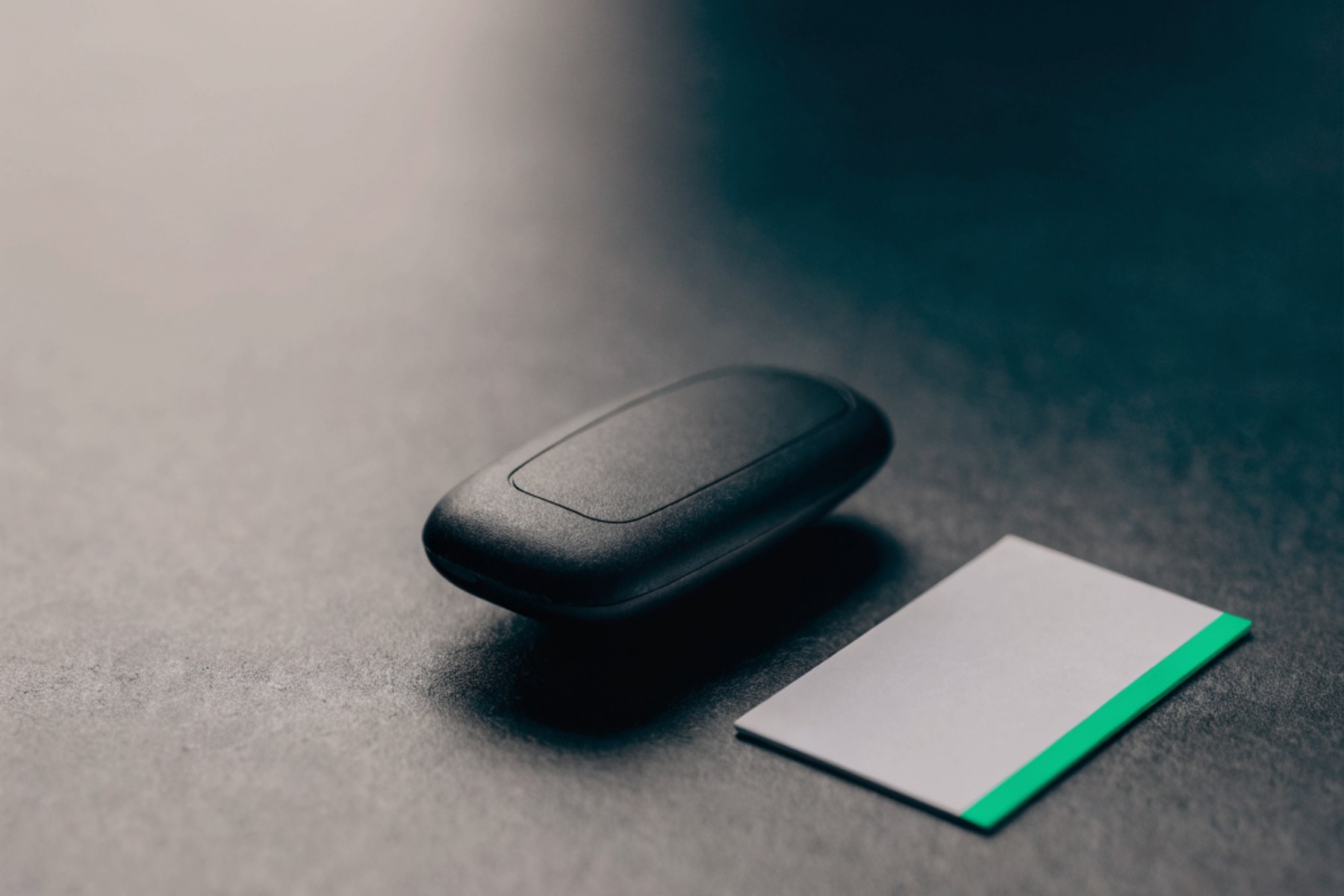 A company car key and a blank card on charcoal, green accent