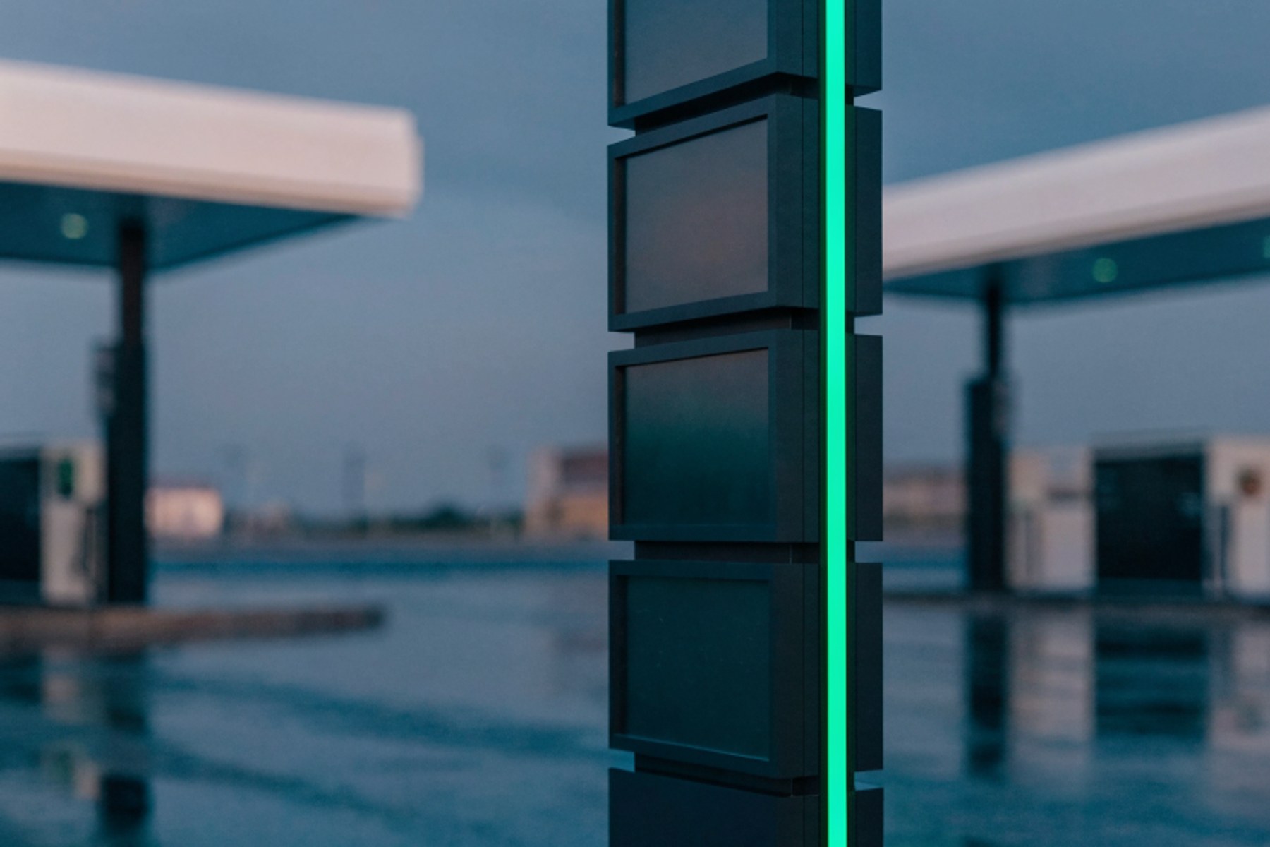 A fuel price totem at dusk, its display blank, green accent
